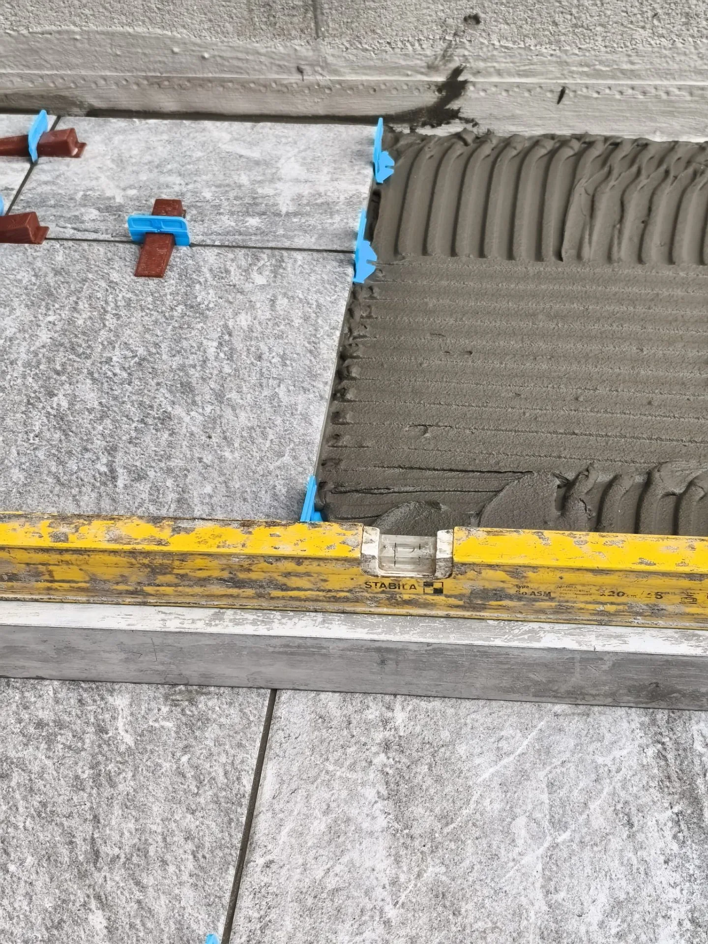 Dettaglio posa: colla pettinata e livellatori — Pavimenti a Modena